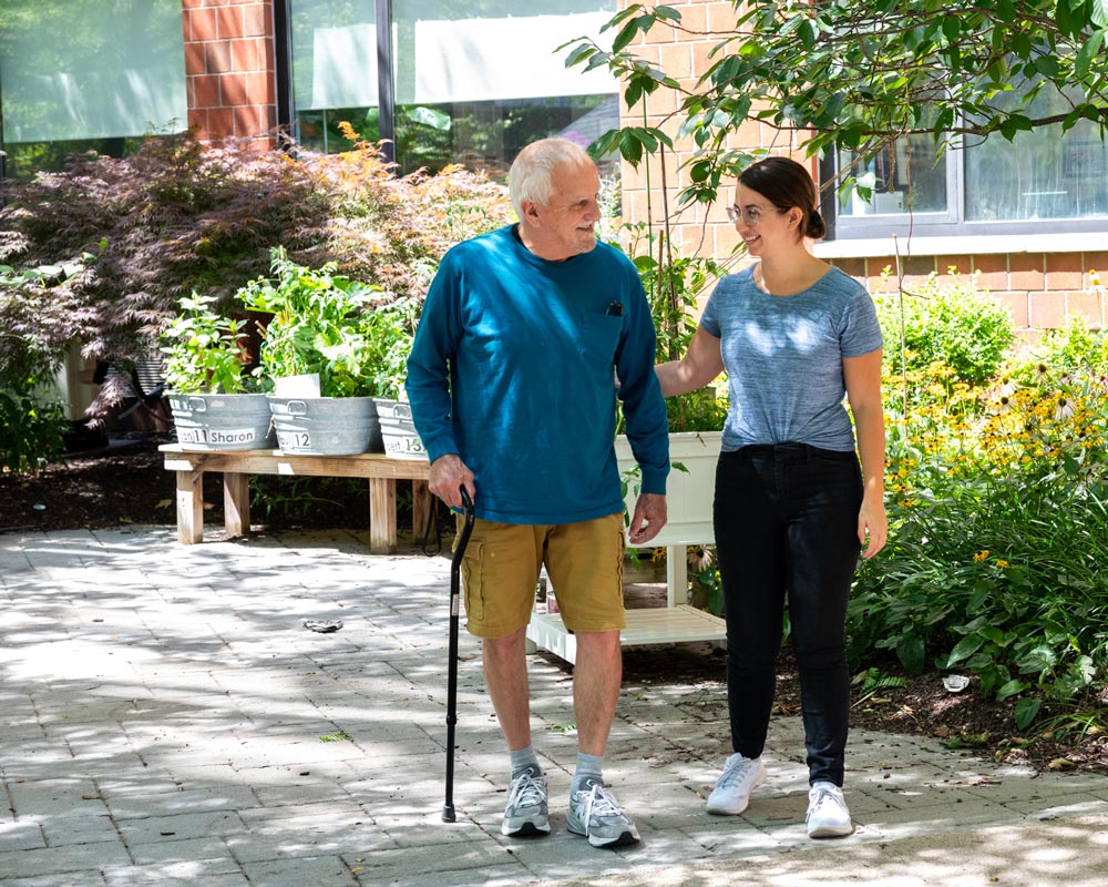 Senior Jewish man walking with young female caregiver